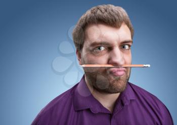 Strange bearded man holds pencil with his nose and lips 