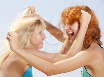Two aggressive women in bikini pulling out hair each other