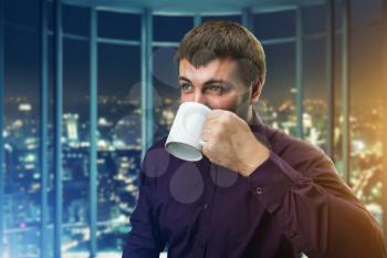Man drinking coffee in office in the evening