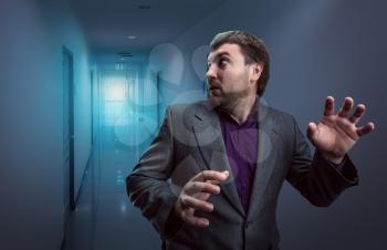 Scared businessman running in the dark corridor