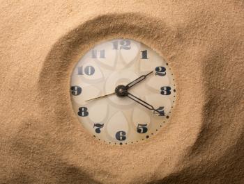 Old alarm clock in sand