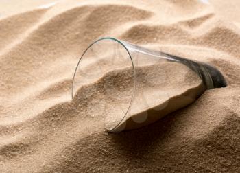 Closeup of empty glass in sand