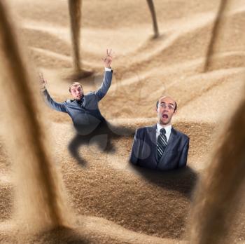Two businessmen fall into the quicksand trap