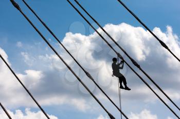 Silhouette of construction climber against blue sky