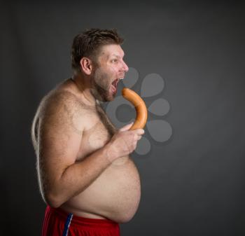 Hungry man eats a big sausaget over grey