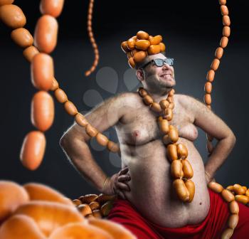 Man sitting with heap of sausages on his head and with sausages round his neck