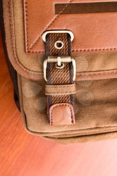 Closeup of brown backpack buckle on wood