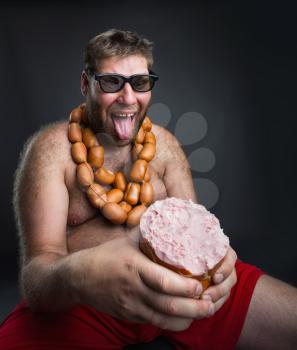 Ugly hungry man with sausages round his neck eats a big wurst over grey