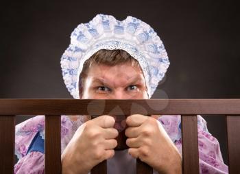 Man weared as baby in playpen looking out