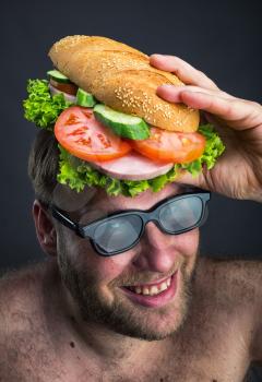 Happy man in glasses holding sandwich on his head 