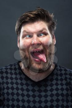 Portrait of bearded man showing his tongue over gray