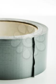 Closeup of a roll of silver adhesive tape on white background