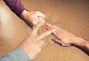 Hands playing paper rock scissors on brown background