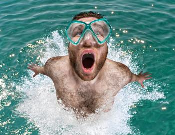Man with swimming mask leaping out from water to breath air