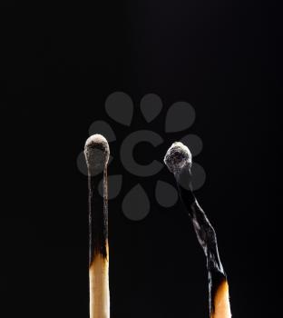 Two burned out wooden matches on black background