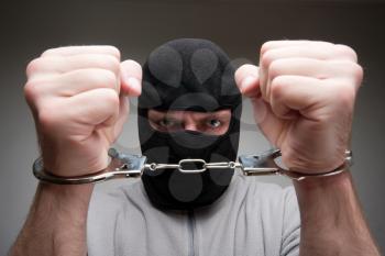 Close-up of angry criminal locked in handcuffs