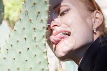 Man touching sharp cactus by tongue