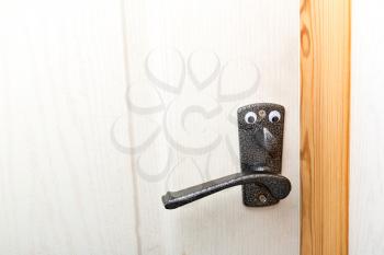 Handle of white wooden door with toy eyes