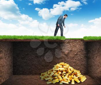 Businessman bends and looks at the treasure in the soil