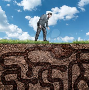 Businessman stands and looks at the underground maze in soil
