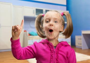 Little girl points her finger up in casual interior