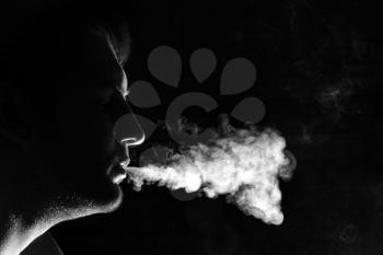Silhouette of smoker exhales smoke