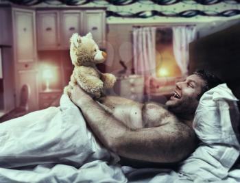 Adult man at home looks at toy bear in the evening
