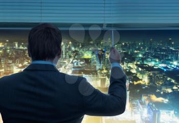 Businessman is looking through the window with night city view