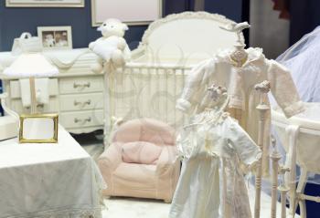 Baby bedroom with white teddy bear and dresses on the chair