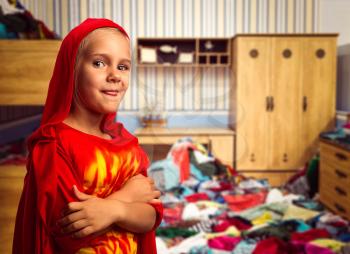 Little girl in masquerade costume in the room with heap of clothes