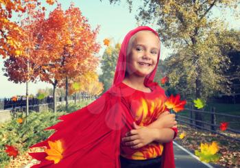 Little girl in masquerade costume in an autumn street