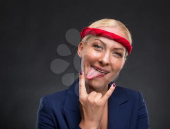 Funny businesswoman showing heavy metal hand gesture over gray background