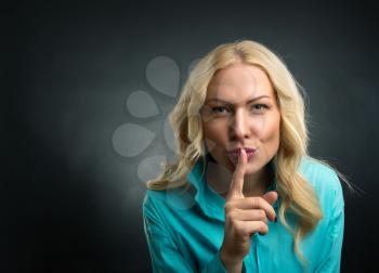 Blonde woman showing silence hand sign
