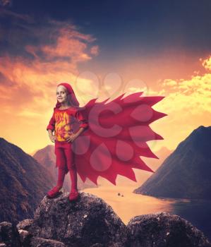 Smiling girl in superhero costume in mountains near the river
