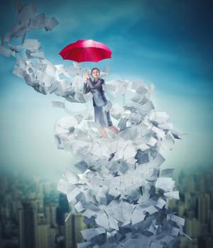 Businesswoman is flying on a red umbrella in paper tornado over downtown