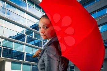 Close up of businesswoman with red umbrella near the office building