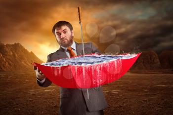 Businessman with red umbrella full of water at night