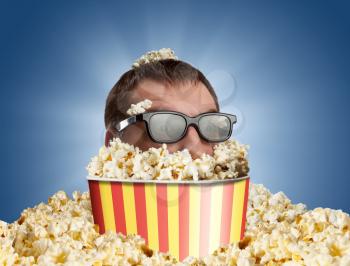 Man in glasses in a bucket of popcorn against blue