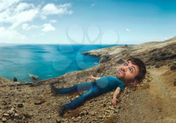 Man with a huge head lying on the coast of the sea