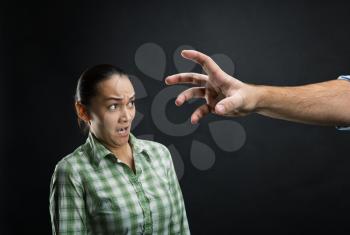 Young woman frightened with huge human hand over black