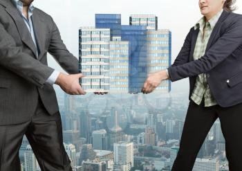 Businesspeople fighting holding in their hands big office buildings