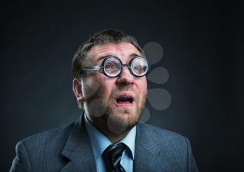 Surprised nerd businessman in glasses over grey