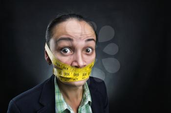 Businesswoman with tape ruler round her face over grey