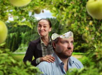 Businesswoman is eating businessman's head as an apple in the garden