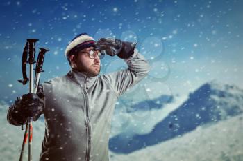 Bearded retro man in glasses in winter mountains looking out