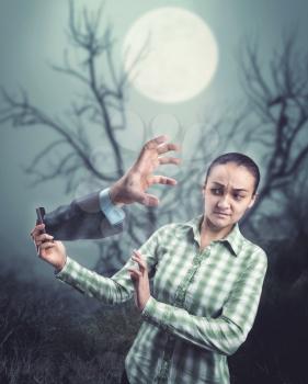 Businesswoman hand with a phone with man's hand from it in the forest at night