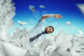 Businessman in glasses swimming in papers