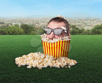 Man in glasses in a bucket of popcorn in the meadow