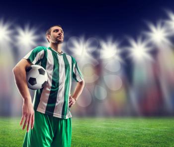 Football-player holding a ball against light