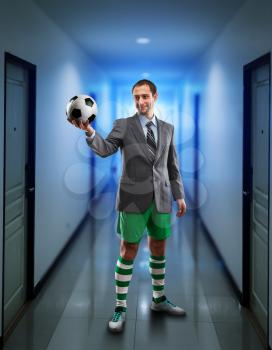 Businessman with suitcase in sportwear holding a ball in the office